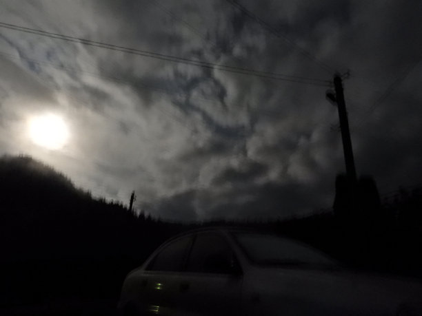 这张照片是用专业相机从地球上拍摄的月亮在云层中与森林相衬的照片图片下载