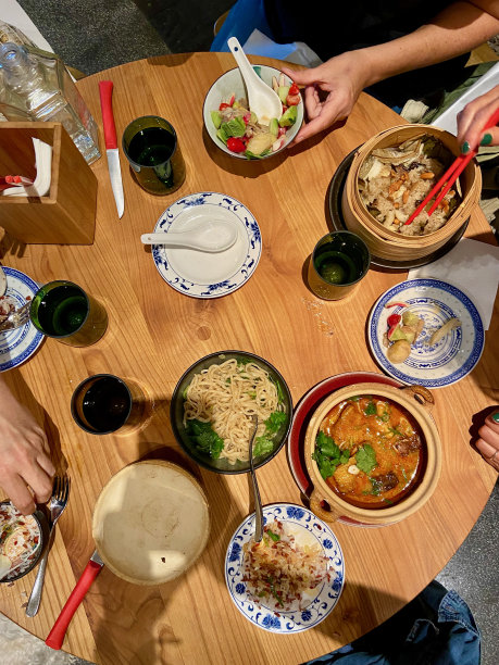 在巴黎一家时髦的中餐馆里，手臂的影子在摆满食物的桌子前拿着手机拍照图片下载