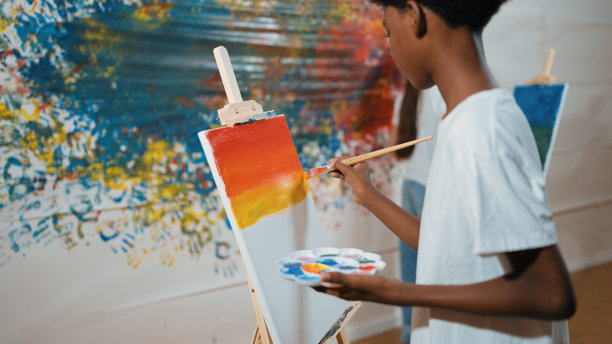 特写非洲男孩手绘画布与暖色调的颜色。启迪。图片下载
