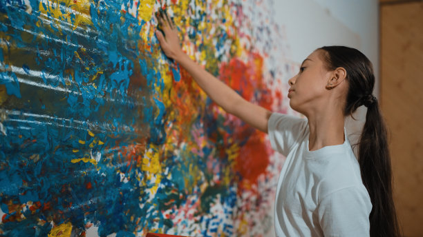 穿着休闲衬衫的女孩站在那里，画着彩色的墙壁。启迪。图片下载