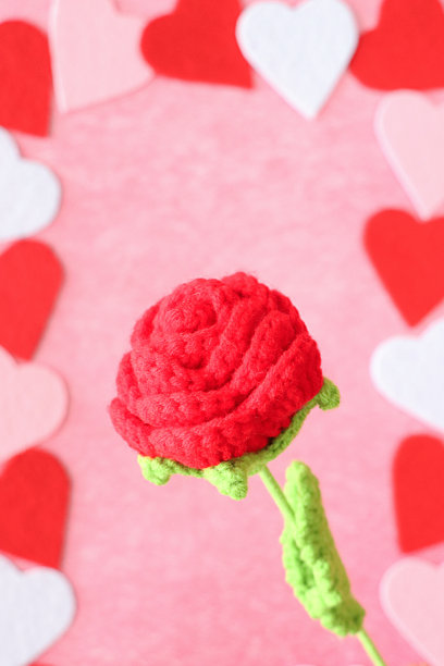 情人节设计海报框架的特写图片，由红色、粉色和白色相间的心形图案围绕着钩针编织的玫瑰，斑驳的粉色背景，抬高的视野，情人节和浪漫的概念图片下载