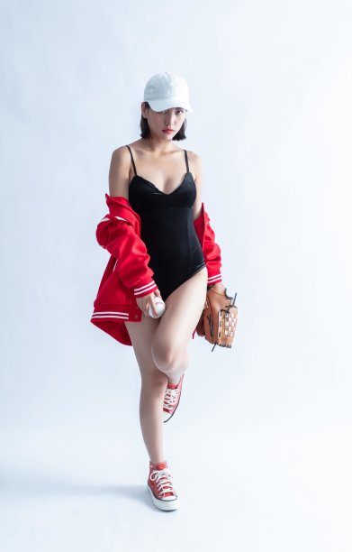 戴着棒球帽、身穿紧身衣和红色夹克的亚洲妇女，手里拿着棒球和手套图片下载