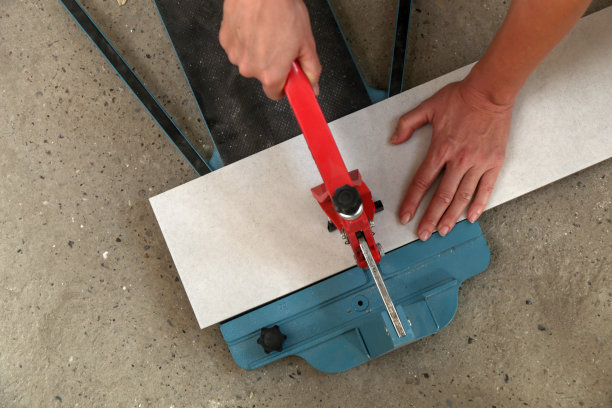 使用标准的手动瓷砖切割机切割瓷砖。瓷砖在浴室中逐步安装的过程。DIY家居装修。图片下载