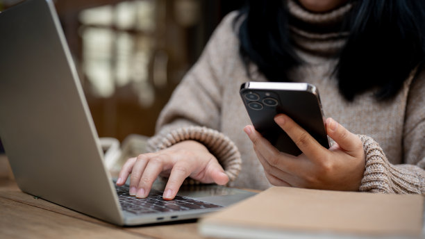 一名亚洲女性在咖啡馆使用智能手机和笔记本电脑的剪辑照片。图片下载