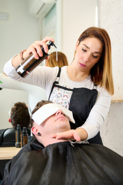 理发师在理发店给男人刮脸前把热毛巾放在他脸上图片下载