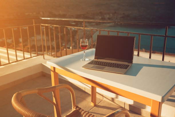 笔记本电脑和一杯酒。是远程工作的理想场所。图片下载