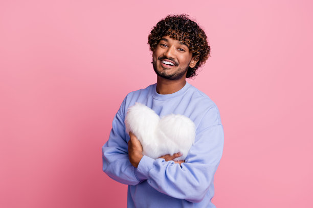 照片中，年轻微笑的英俊男友抱着毛茸茸的枕头，象征着对女友的爱意图片下载