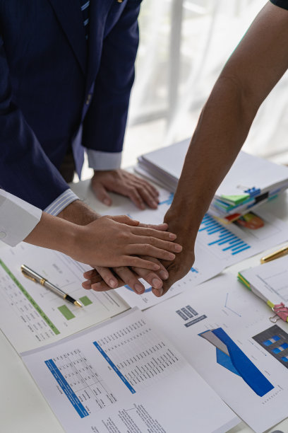 商人和投资者握手作为友谊和合作的象征，在商业合作成功和文件，财务图表和笔记本电脑在桌子上。特写照片。图片下载