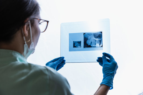 年轻的女牙医正在检查病人的全景牙科x光照片图片下载