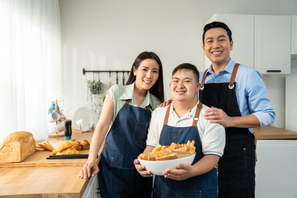 亚洲家庭的父母和儿子在厨房烤面包的照片。美丽的恩爱夫妻妈妈和爸爸照顾和教年轻人在家里做饭。生活方式的活动图片下载