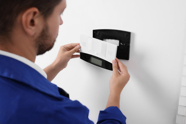 技术员在室内白墙上安装家庭安全报警系统，特写图片下载