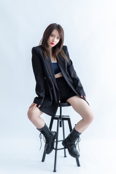 穿着黑色西装外套和短裤的亚洲妇女坐在椅子上图片下载