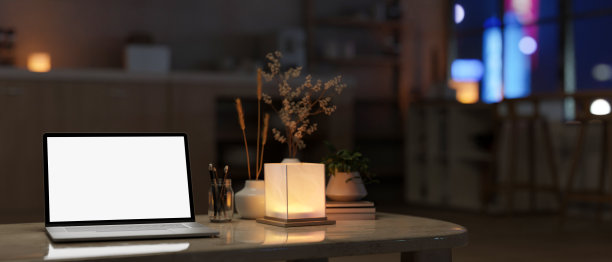 一台笔记本电脑，一盏台灯，在一个现代黑暗的客厅里，咖啡桌上的配件。图片下载