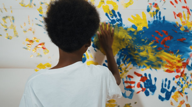 快乐的非洲男孩的后景，用手画着污迹斑斑的墙壁。启迪。图片下载