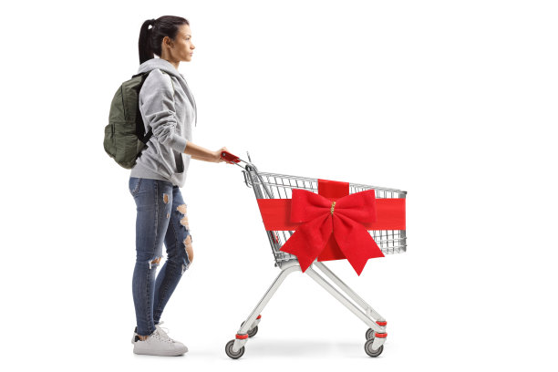 一个女学生的全身侧面照片，她拿着一个空的购物车，用红丝带系着蝴蝶结图片下载