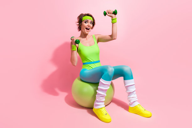 照片兴奋的教练女士练习健身练习与适合球哑铃孤立柔和的颜色背景图片下载