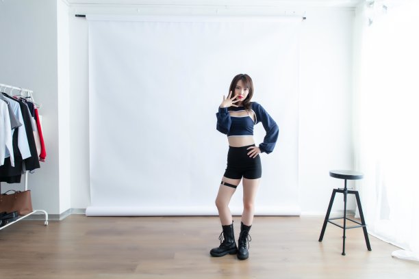 一名身穿蓝色露脐上衣和黑色短裤的亚洲女子在摄影棚里摆姿势图片下载