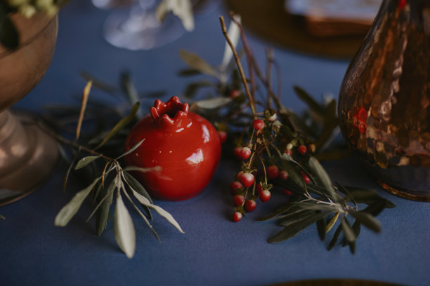 波希米亚风格的婚礼餐桌，装饰着一个蓝色覆盖的青铜花瓶和石榴雕像。库存图片图片下载