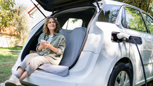 一个女人坐在电动汽车的后备箱里。图片下载