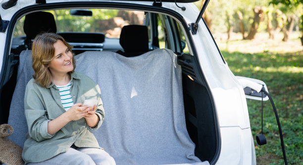 一个女人坐在电动汽车的后备箱里。图片下载
