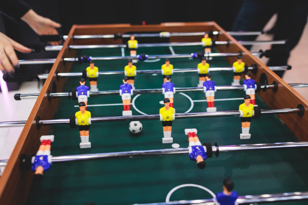 一群朋友在体育酒吧玩踢球，同事队友玩桌上足球，在办公室玩桌上足球，在工作中玩桌上足球比赛图片下载