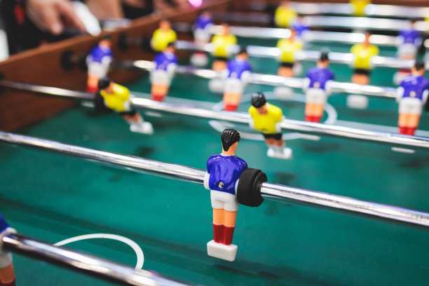一群朋友在体育酒吧玩踢球，同事队友玩桌上足球，在办公室玩桌上足球，在工作中玩桌上足球比赛图片下载