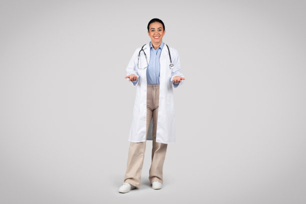 开朗的拉丁女医生微笑着对着镜头摆姿势，穿着白色制服，灰色背景，全身图片下载