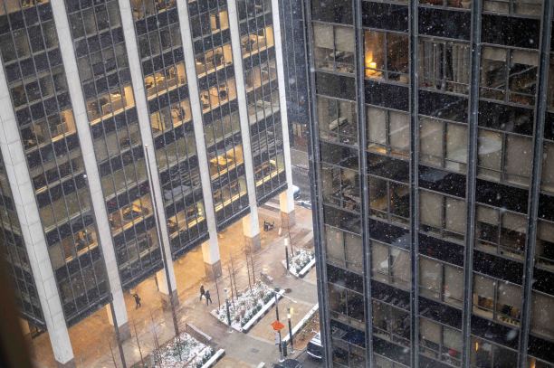 鸟瞰图，雪落在城市的城市景观，办公室和住宅楼人行道上的行人图片下载