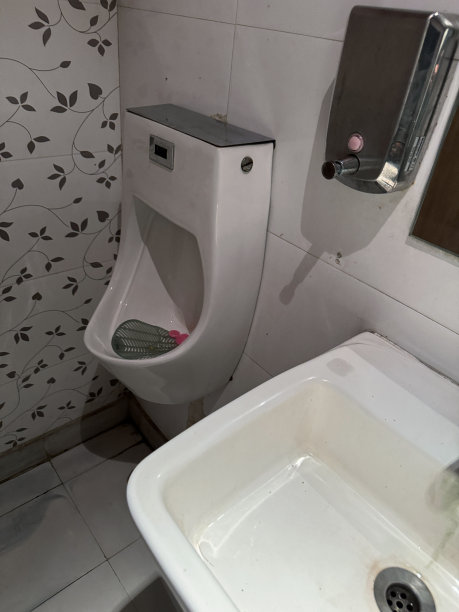 公厕厕所小便池特写图片，白色陶瓷小便池，蓝色PVC，有香味的小便池屏幕在碗里，背景飞溅，干净卫生的小便池，墙内有排水管和排水管，绿色大理石效果的石材瓷砖地板图片下载