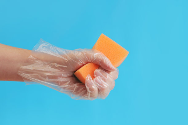 手里拿着海绵，湿地打扫房间，明亮的蓝色背景图片下载