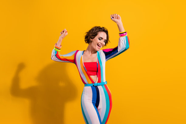 照片上的女孩穿着鲜艳的衣服，举起手，有乐趣的跳舞，夜总会主题派对孤立在黄色的背景图片下载