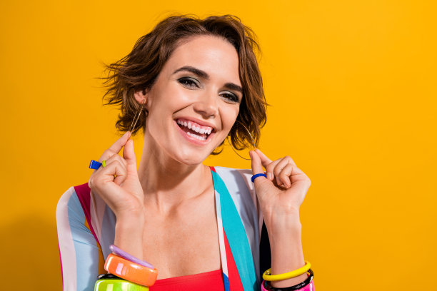 照片的华丽迷人的妖艳女子棕色鲍勃头发触摸金色耳环的时尚派对孤立的黄色背景图片下载