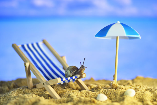 海滩上的蜗牛。海边的躺椅。以度假为主题的概念性宏观照片图片下载