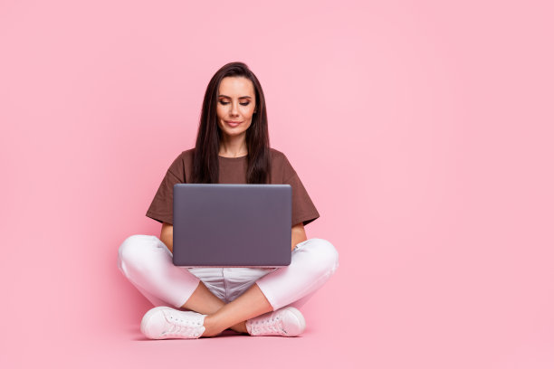 年轻集中的商业妇女的全身照片创建教育课程的孩子与笔记本电脑孤立的粉红色背景图片下载