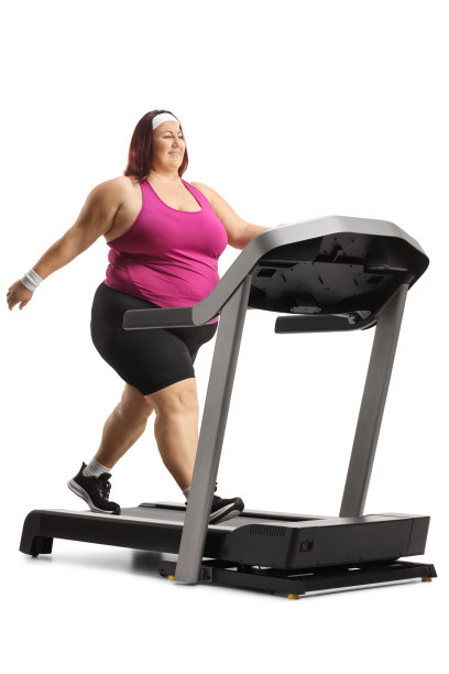 一个大码的女人在跑步机上行走的全长照片图片下载