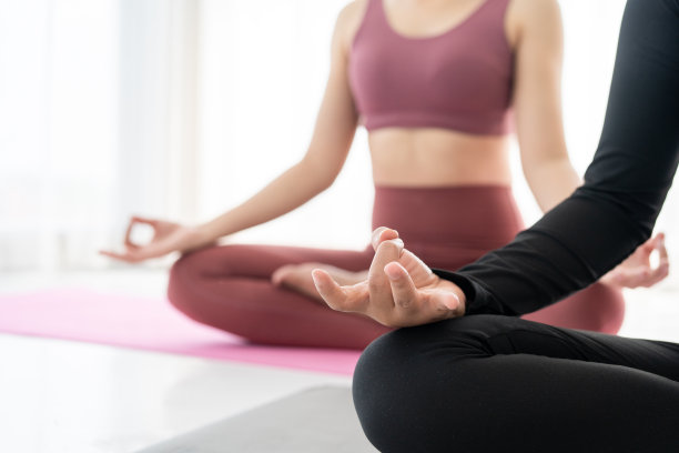 两个年轻美丽的亚洲运动女性坐在瑜伽垫上练习冥想。在家健身或锻炼。美丽的女性在锻炼后放松。图片下载