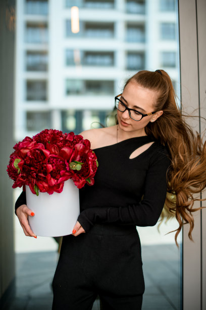 女人手中的白色礼盒里装着一束豪华的深红色牡丹图片下载