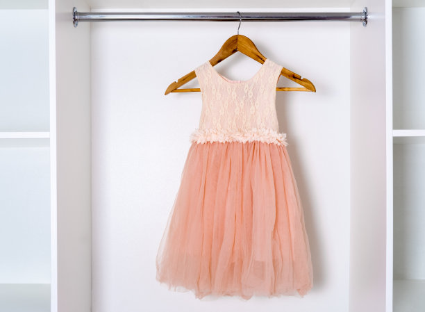 优雅的桃色连衣裙挂在白色衣柜的木架上。图片下载