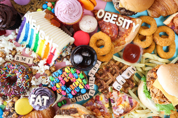 全画幅的字母骰子和木制字母拼出“脂肪”，“BMI”，“不健康”，“饮食”，“肥胖”和“体重”的甜垃圾食品，一杯冰可乐，芝士汉堡，碎洋葱圈，披萨片，土豆华夫饼，釉面圈甜甜圈图片下载