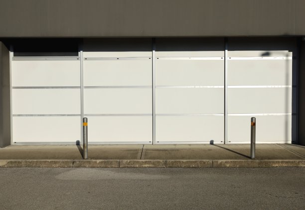 立面上有白色的遮帘窗。有固定护柱的混凝土人行道和前面的街道。图片下载