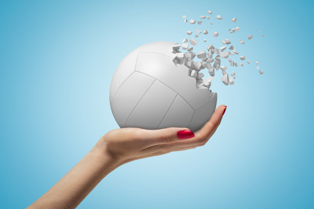 在蓝色背景下，女性手握的白色排球碎成碎片图片下载