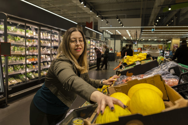 戴着圆眼镜、蓝头发的女人在商店里购物。她看着这些产品，想着该选什么。库存图片图片下载