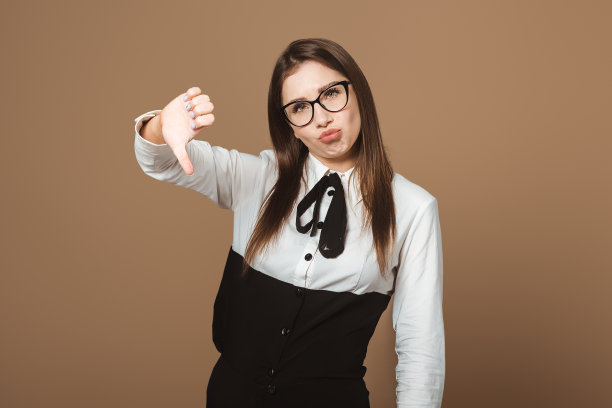不满意的女士用皱眉和大拇指朝下的手势表示不赞成。说明负面反馈、不满和批评的概念照片图片下载