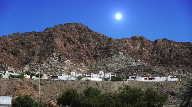 白色村庄房屋上方的崎岖沙漠山脉图片下载