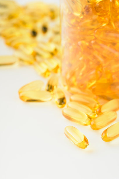近距离胶囊与维生素D, E或欧米茄3,6,9脂肪酸在瓶的顶部视图隔离在白色。食品补充油填充鱼油。天然补品健康美好生活理念。横幅。图片下载