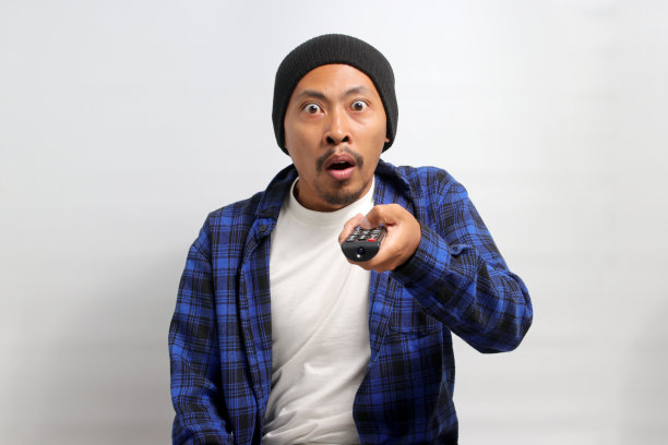 惊讶的年轻亚洲男子在电视上看到令人震惊的新闻图片下载