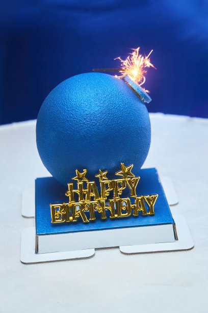 一个炸弹形状的生日蛋糕。点燃的保险丝。“生日快乐”的题词图片下载