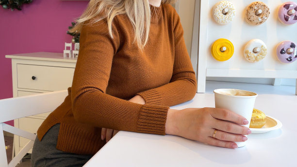 女性手拿甜甜圈和一杯咖啡的特写。图片下载