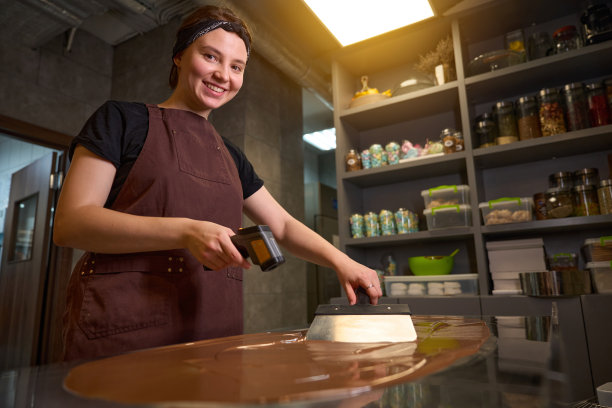 快乐的女巧克力师忙着在厨房的工作台上加工巧克力图片下载