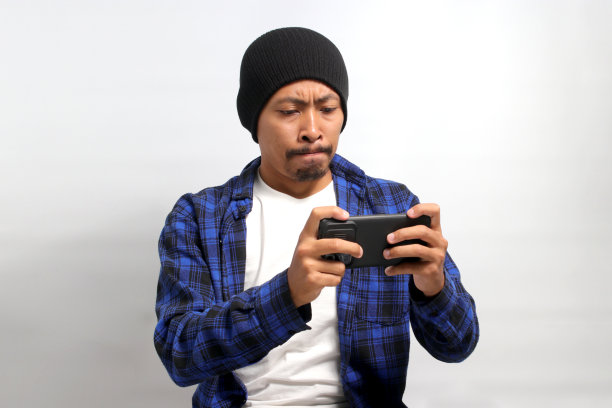 一名亚洲男子正全神贯注地在手机上玩游戏图片下载